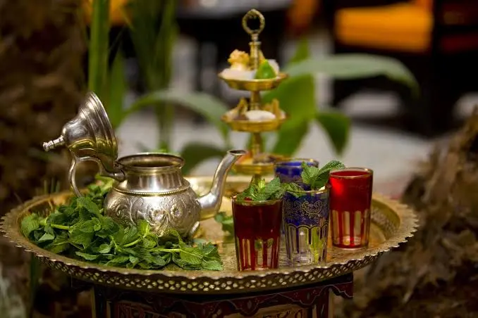 Alt Text: Traditional Moroccan silver teapot and colorful mint tea glasses served on a brass tray.